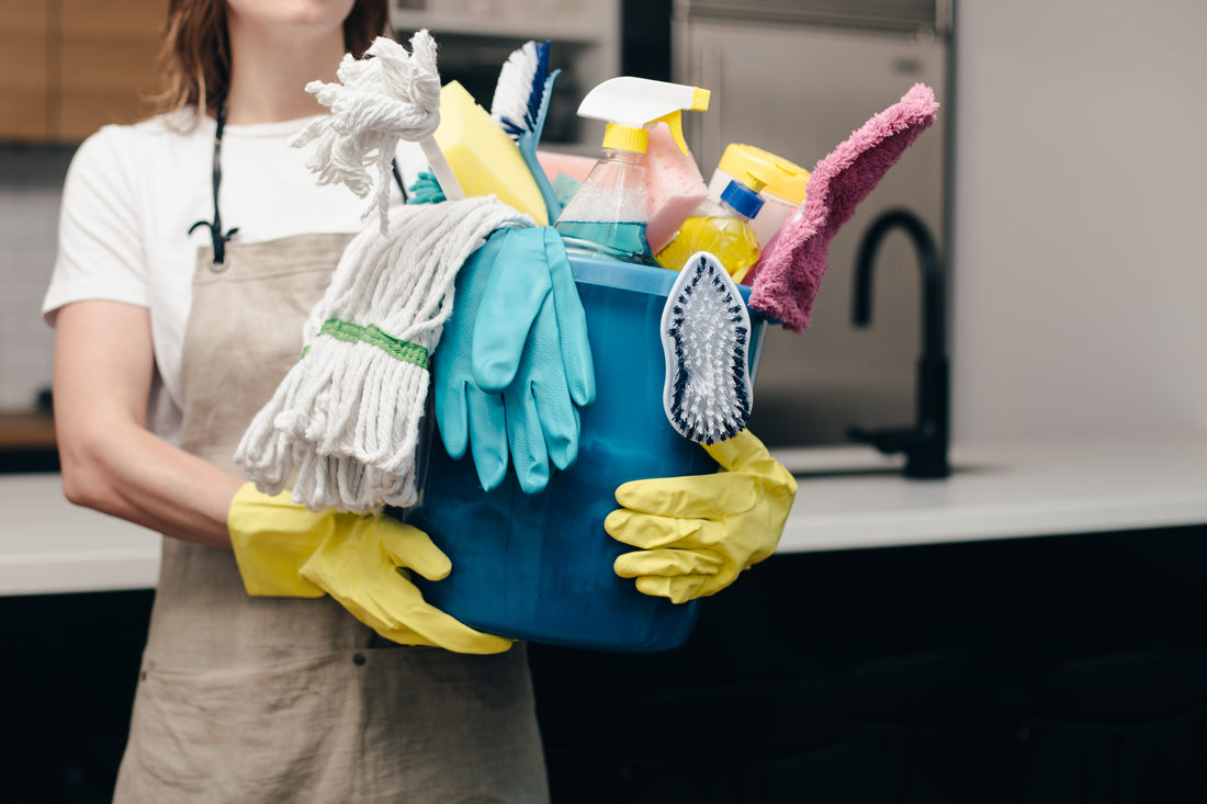 person holding bucket of cleaning supplies 