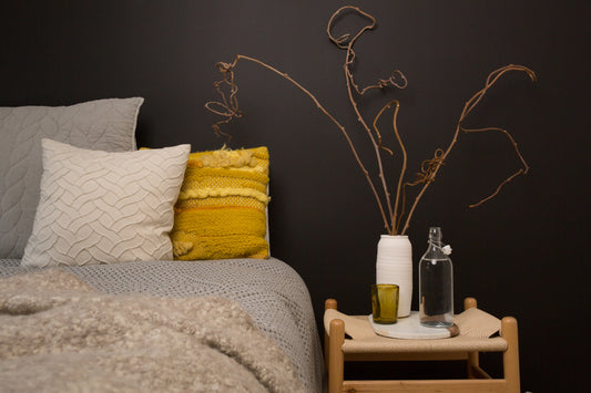 Guest-ready Airbnb bedroom with bed and styled bedside table featuring plant, water jug and glass 