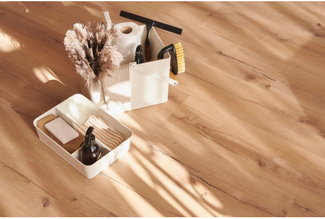 Cleaning tools including a brush, squeegee, and bottle on a wooden surface.